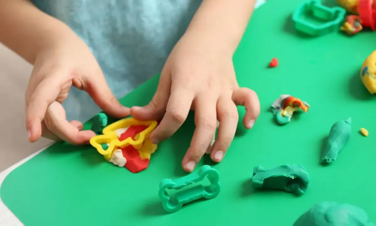 Dziecko bawi się kolorową modeliną i plasteliną, tworząc różne kształty.