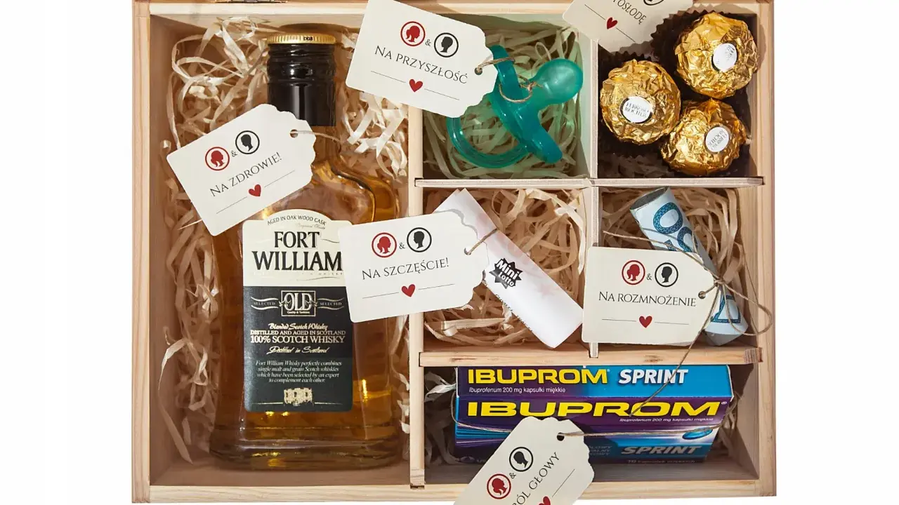 Drewniana skrzynka z zawartością: butelka whisky, smoczek, czekoladki, leki, pieniądze i losy. To idealny **niezbędnik małżeński co włożyć** na szczęście i przyszłość.