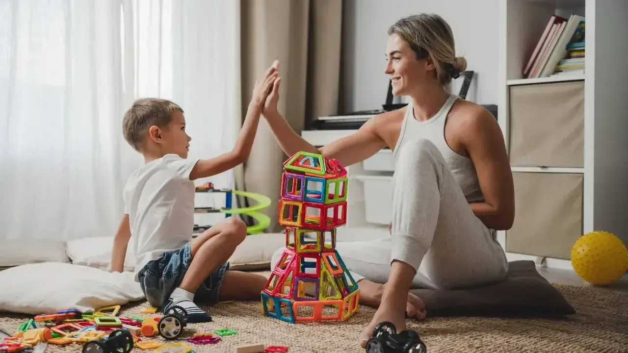 Mama i syn świętują sukces kreatywnych zabaw plastycznych, budując wieżę z kolorowych klocków.
