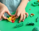 Dziecko bawi się kolorową modeliną i plasteliną, tworząc różne kształty.