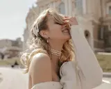Uśmiechnięta blondynka w perłowej biżuterii, z perłową spinką we włosach. Masa perłowa znaczenie symbolizuje czystość i piękno.
