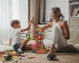 Mama i syn świętują sukces kreatywnych zabaw plastycznych, budując wieżę z kolorowych klocków.