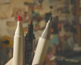 Trzy markery, jeden z czerwoną końcówką, jeden czarny Winsor & Newton i jeden szary, gotowe do tworzenia dzieł sztuki.