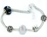 Bransoletka z zawieszkami: czarna z literą S, serca, kwiat, korona. Wytrzymałość gumki jubilerskiej zapewnia bezpieczeństwo ozdób.