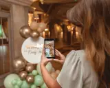 Kobieta robi zdjęcie dekoracji na baby shower. Złote i miętowe balony tworzą łuk. Świetne baby shower pomysły!