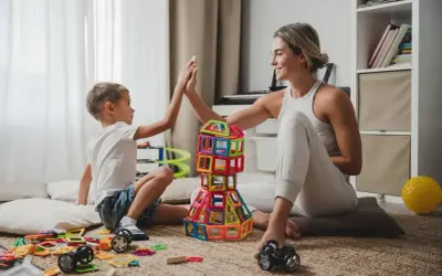 Mama i syn świętują sukces kreatywnych zabaw plastycznych, budując wieżę z kolorowych klocków.