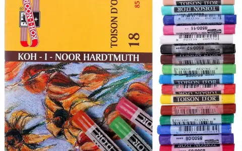 Pudełko z pastelami Koh-i-Noor i stos kolorowych pasteli olejnych.