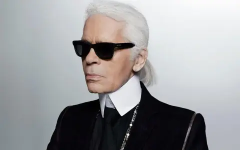 Ikona stylu, Karl Lagerfeld, w czarnym garniturze i okularach. Kto to? Ikona mody.