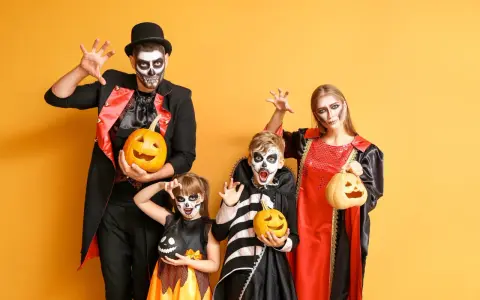 Rodzina w strojach na Halloween z dyniami i makijażem czaszki na żółtym tle.