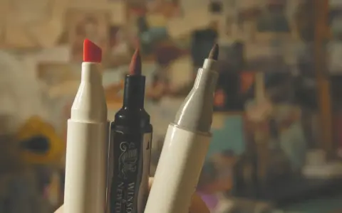 Trzy markery, jeden z czerwoną końcówką, jeden czarny Winsor & Newton i jeden szary, gotowe do tworzenia dzieł sztuki.