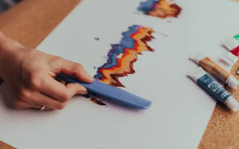 Rysowanie tęczowych fal grzebieniem to świetny pomysł, co można namalować farbami dla dzieci.