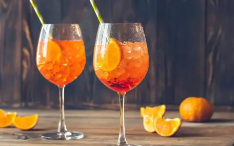 Dwa orzeźwiające drinki Aperol Spritz, idealne, by dowiedzieć się, jak zrobić pomarańczowy. Z plastrem pomarańczy i słomką.