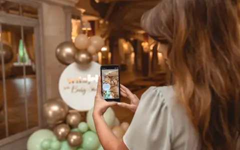 Kobieta robi zdjęcie dekoracji na baby shower. Złote i miętowe balony tworzą łuk. Świetne baby shower pomysły!