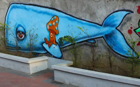Niebieski wieloryb z grzybkiem na grzbiecie. Inspiracja, jak zrobić mural na kartce, w miejskim krajobrazie.