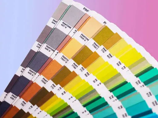 Próbnik kolorów Pantone prezentuje bogactwo barw, od stonowanych szarości po jaskrawe zielenie i żółcie. To narzędzie niezbędne w praktycznym zastosowaniu teorii koloru.