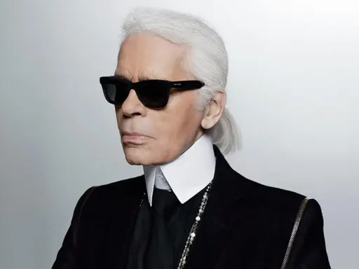 Ikona stylu, Karl Lagerfeld, w czarnym garniturze i okularach. Kto to? Ikona mody.