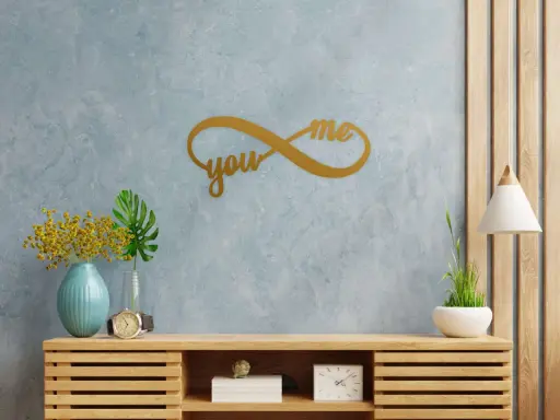 Złoty symbol nieskończoności z napisami "you" i "me" na niebieskiej ścianie, symbolizujący wieczną miłość.
