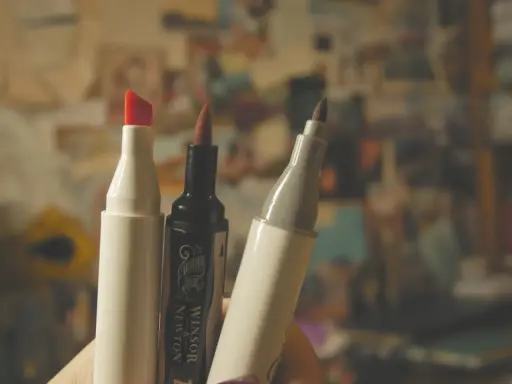 Trzy markery, jeden z czerwoną końcówką, jeden czarny Winsor & Newton i jeden szary, gotowe do tworzenia dzieł sztuki.