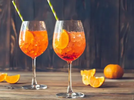 Dwa orzeźwiające drinki Aperol Spritz, idealne, by dowiedzieć się, jak zrobić pomarańczowy. Z plastrem pomarańczy i słomką.