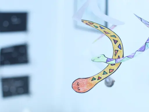 Kolorowy, ręcznie rysowany wąż nieskończoności wiruje w powietrzu, ozdobiony geometrycznymi wzorami.
