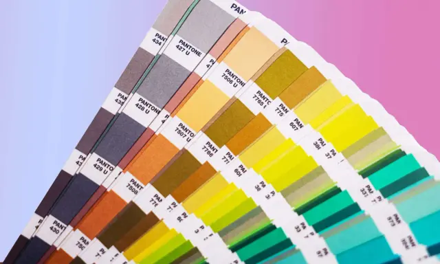 Próbnik kolorów Pantone prezentuje bogactwo barw, od stonowanych szarości po jaskrawe zielenie i żółcie. To narzędzie niezbędne w praktycznym zastosowaniu teorii koloru.