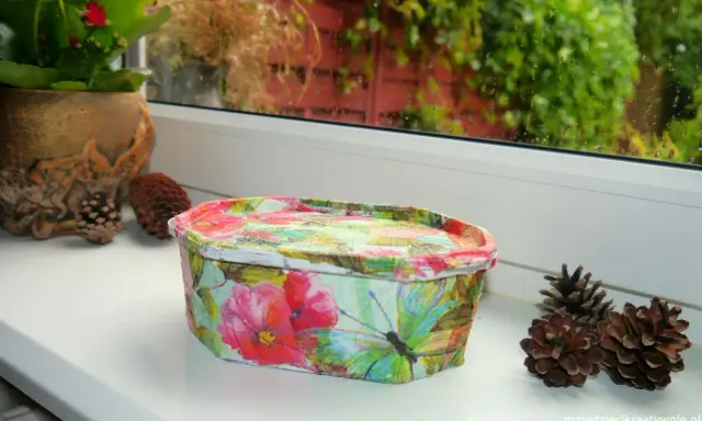 Uroczy koszyczek z motywem kwiatów i motyli, wykonany techniką decoupage na plastiku. Idealny do przechowywania drobiazgów.