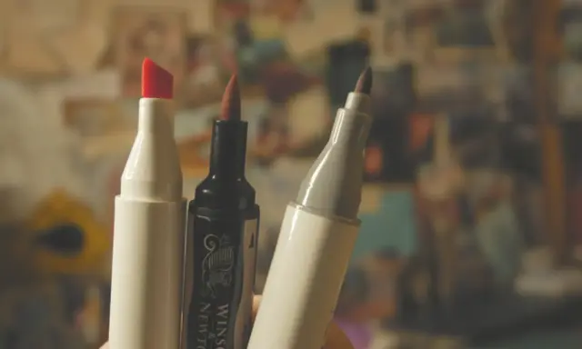 Trzy markery, jeden z czerwoną końcówką, jeden czarny Winsor & Newton i jeden szary, gotowe do tworzenia dzieł sztuki.