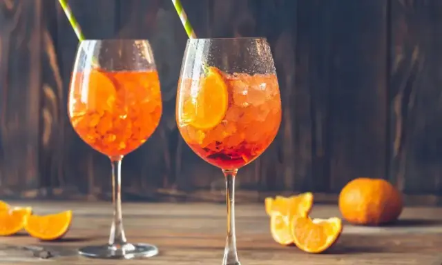 Dwa orzeźwiające drinki Aperol Spritz, idealne, by dowiedzieć się, jak zrobić pomarańczowy. Z plastrem pomarańczy i słomką.