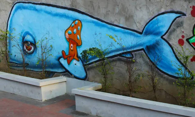 Niebieski wieloryb z grzybkiem na grzbiecie. Inspiracja, jak zrobić mural na kartce, w miejskim krajobrazie.
