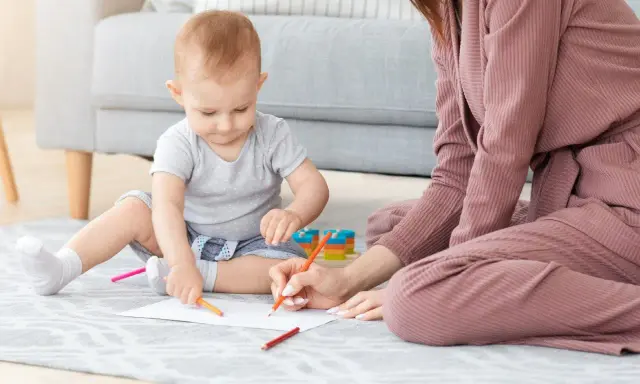 Matka i dziecko rysują kredkami na podłodze.